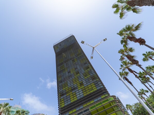A tall, modern skyscraper with a unique, curved facade and a street lamp in the foreground.