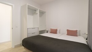 Un dormitorio con una cama, un armario y una mesita de noche.