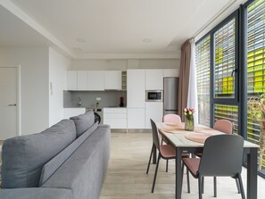 Una cucina moderna con mobili bianchi, forno integrato e frigorifero in acciaio inossidabile.