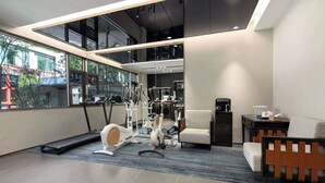 A modern gym with exercise equipment, a treadmill, and a seating area with a coffee machine. - Days Hotel By Wyndham Aba Jiuzhaigou (Ngawa Autonomous Prefecture)