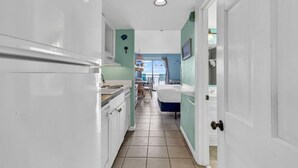 Un pasillo estrecho con una cocina a un lado y un baño al otro, que conduce a un balcón con vistas.