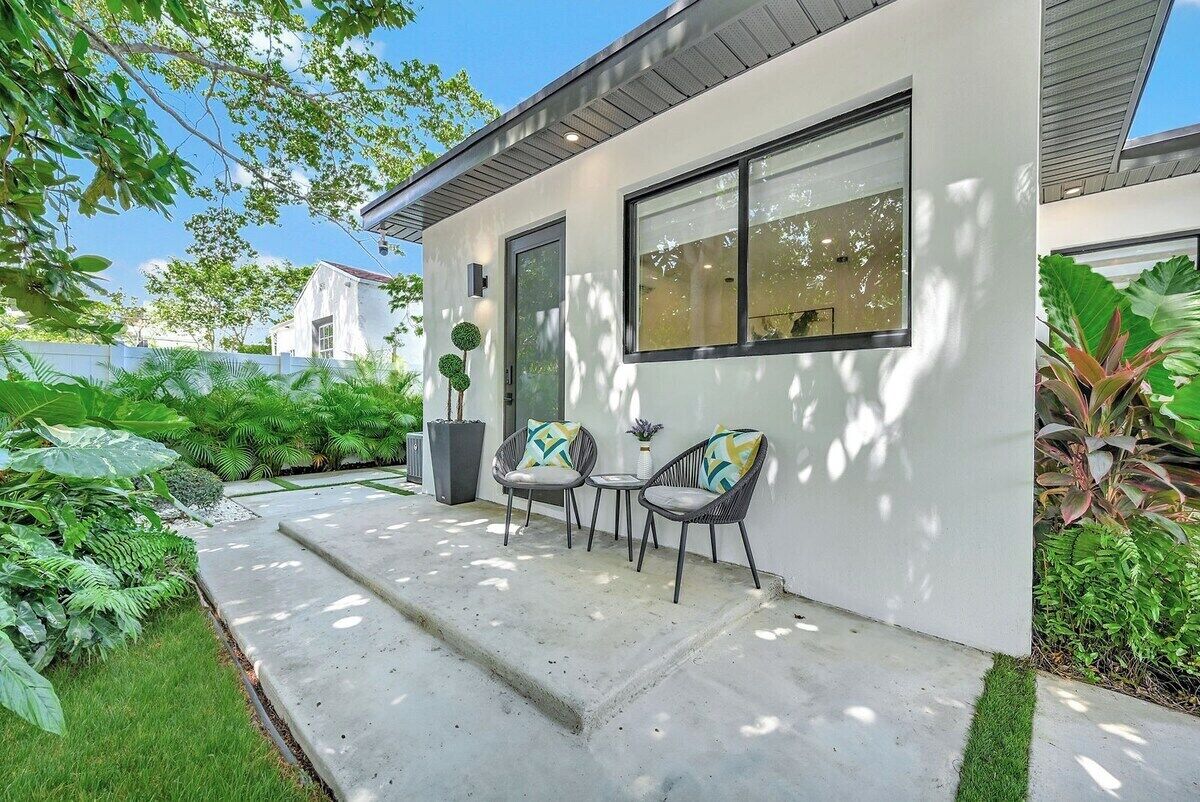 Ein modernes Haus mit Terrasse, zwei Stühlen und einem kleinen Tisch.
