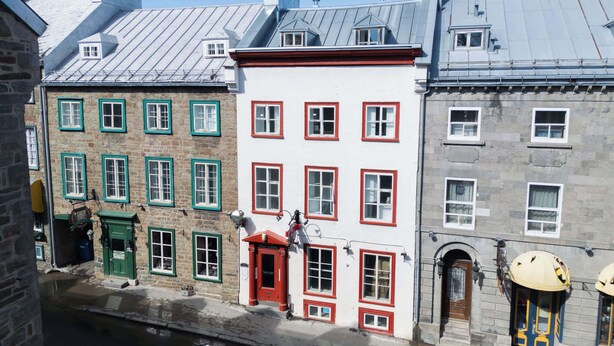 Een rij historische gebouwen met verschillende architectuurstijlen, waaronder gevels van natuursteen en uiteenlopende raamontwerpen.
