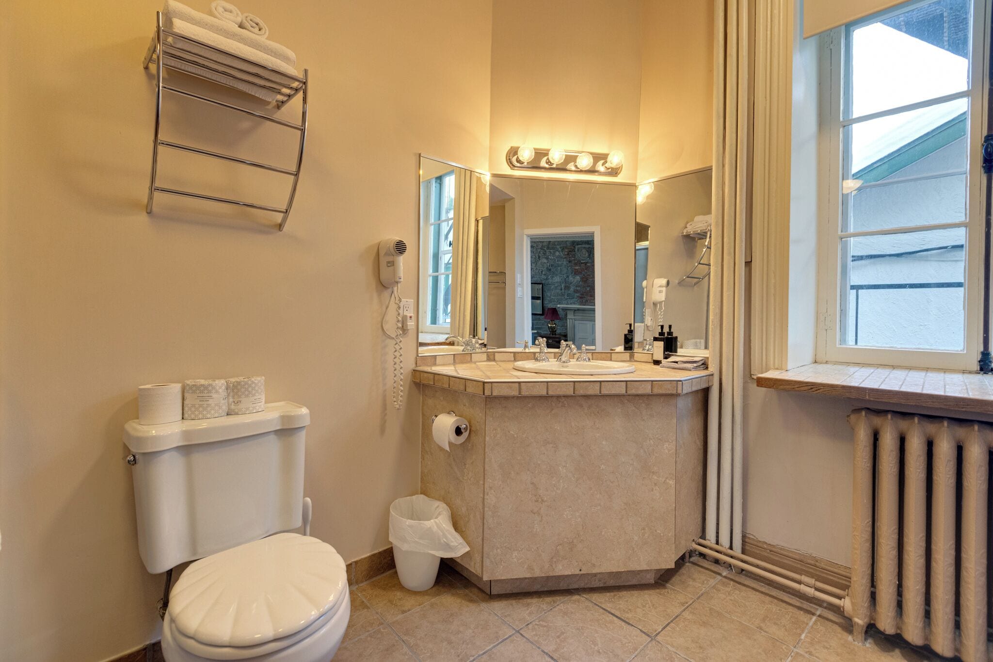 A bathroom with a toilet, sink, vanity, and a window.