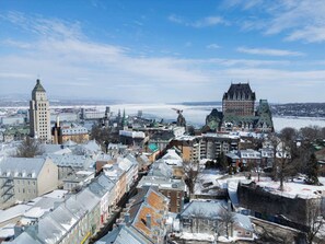A cityscape with historic buildings, including a prominent tower and a large castle-like structure. - Hotel Le Cavalier - M11 (Québec)