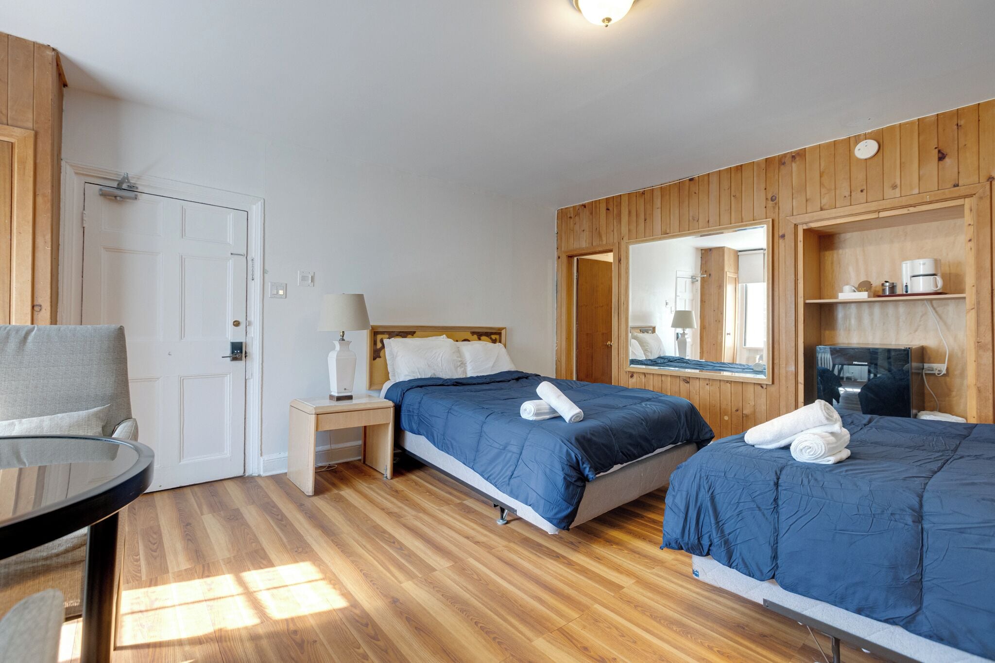 A room with two beds, a desk, a chair, a TV, and a mirror.