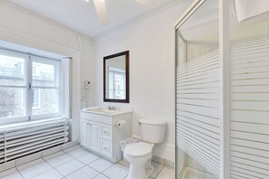 A bathroom with a toilet, sink, and window. - Hotel Le Cavalier - M11 (Québec)