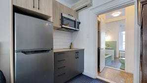 Een kleine keuken met een roestvrijstalen koelkast, een magnetron en houten kastjes.