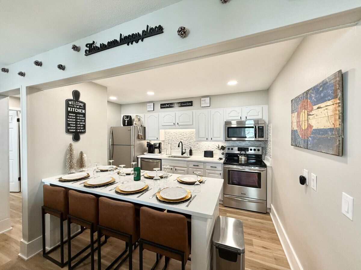 A modern kitchen with white cabinets, stainless steel appliances, and a central island with bar stools.