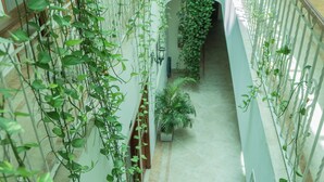 Espacio interior de varios niveles con una escalera central rodeada de abundante vegetación.