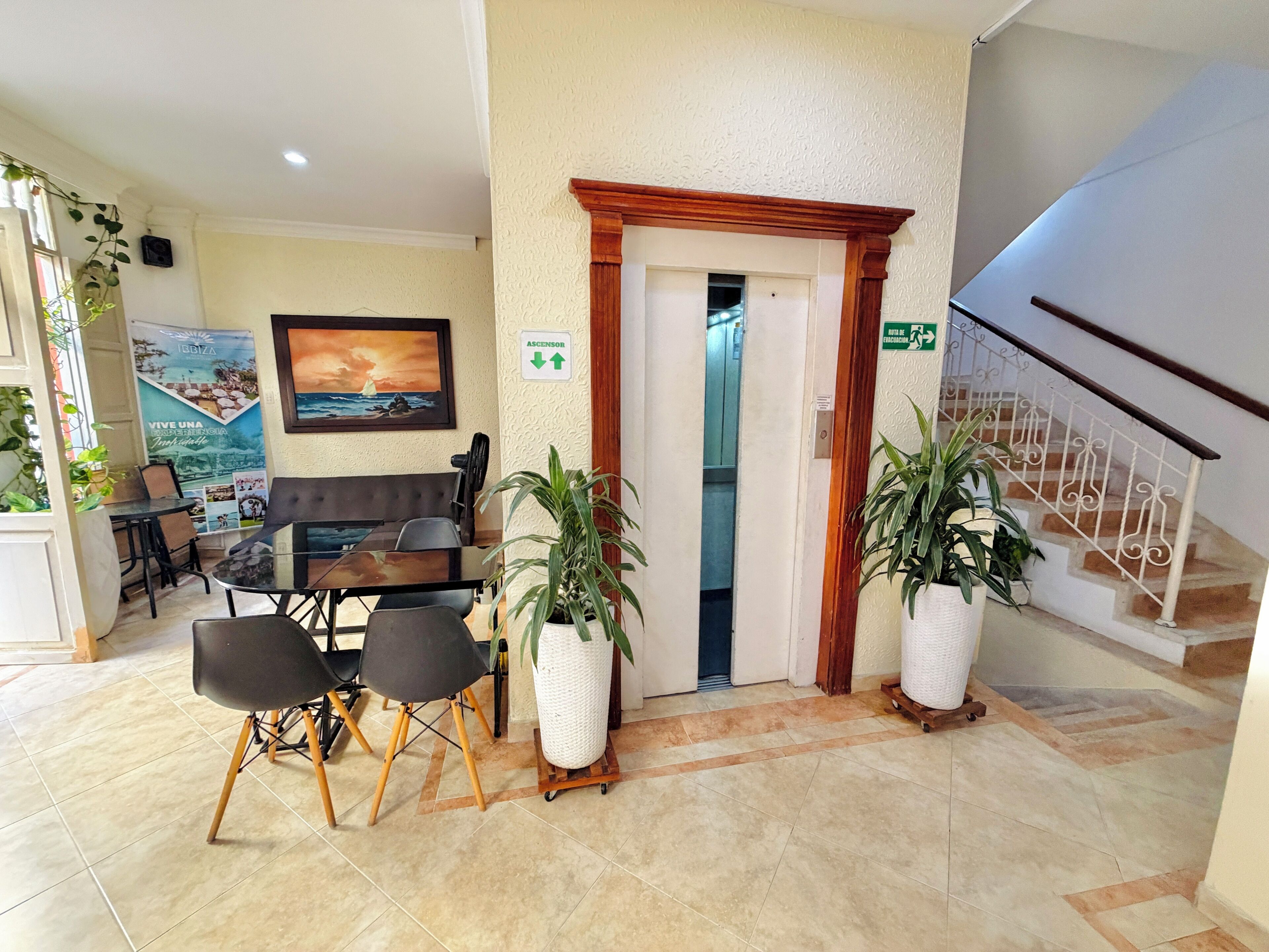 A hotel lobby with a reception desk, seating area, and a staircase.