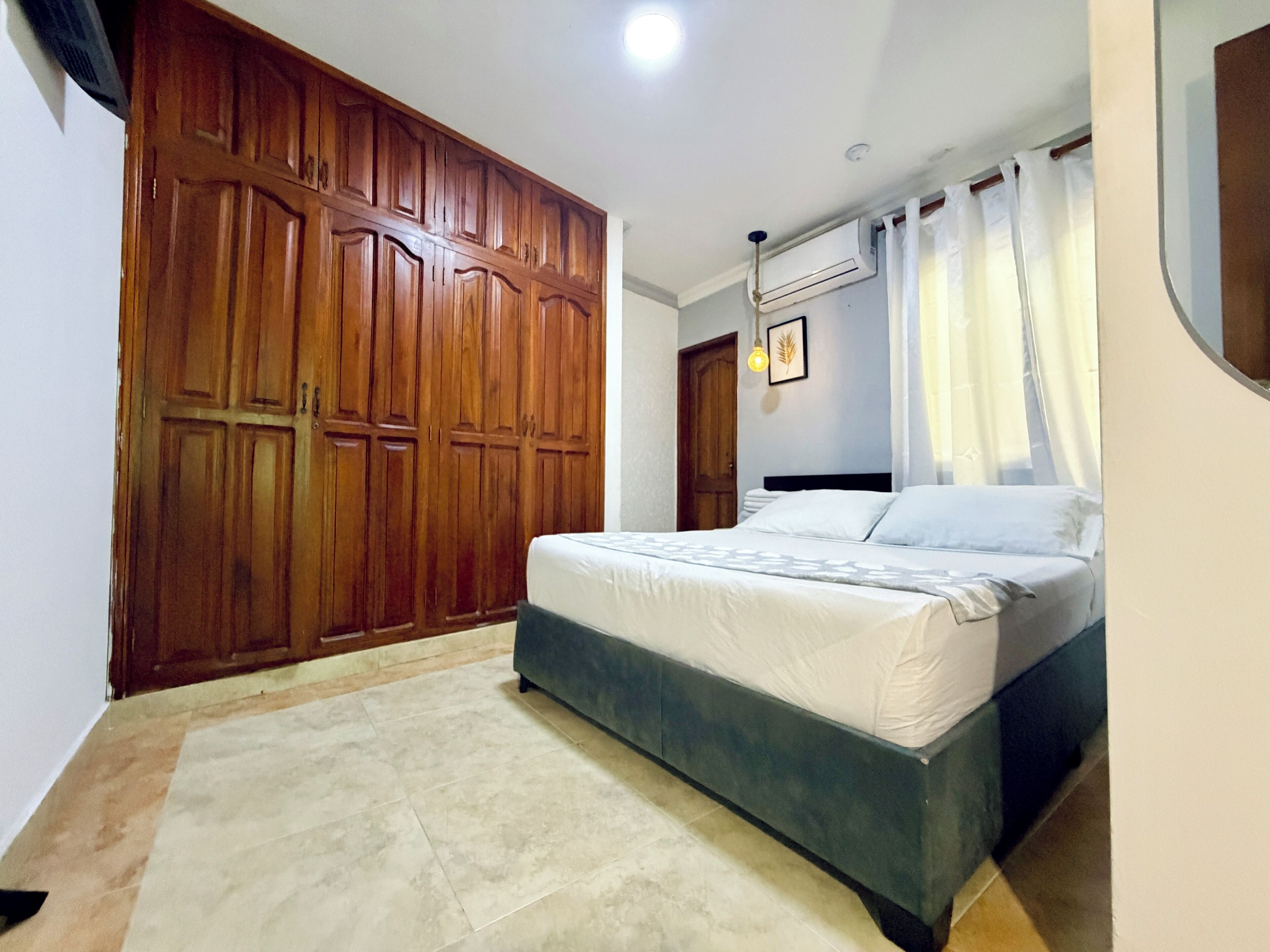 Un dormitorio con cama, armario de madera y ventilador de techo.