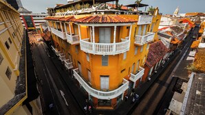 Un edificio de varios pisos con balcones, una calle estrecha y edificios colindantes.