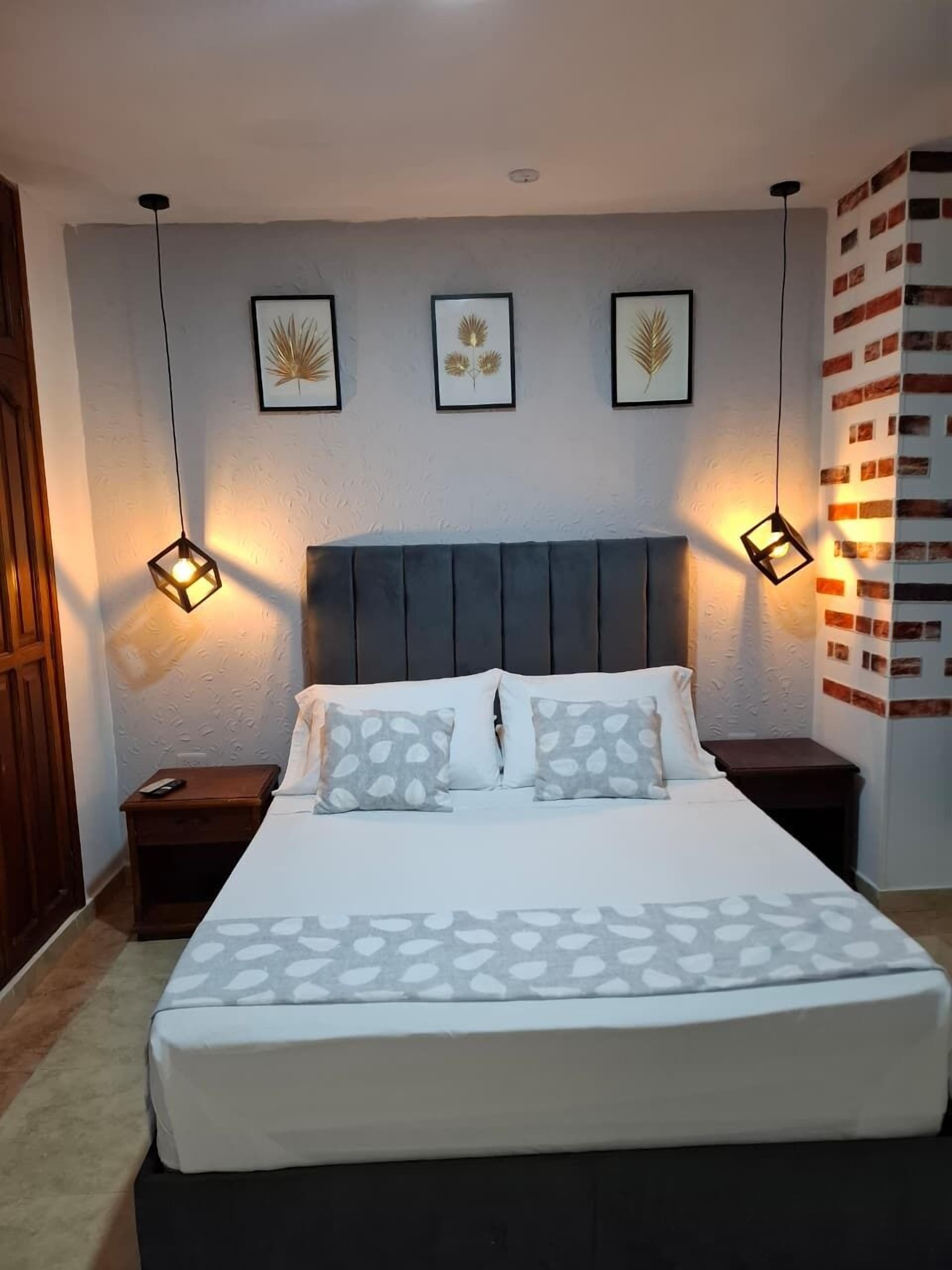 A neatly arranged bedroom with a bed, two bedside tables, and three wall-mounted pendant lights.