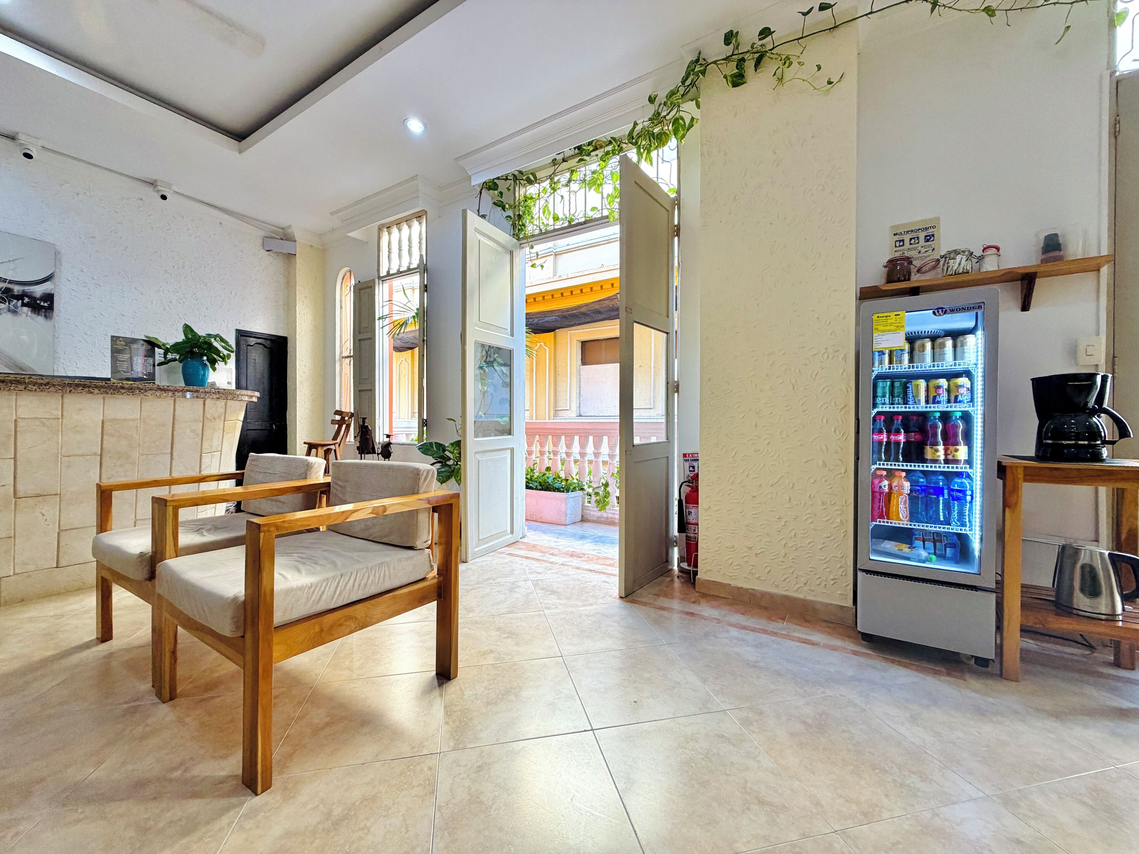 A hotel lobby with a seating area, a refrigerator with beverages, and a coffee machine.