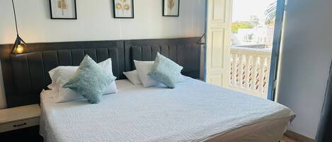 Une chambre avec un grand lit, une tête de lit et trois œuvres d’art encadrées accrochées au mur.
