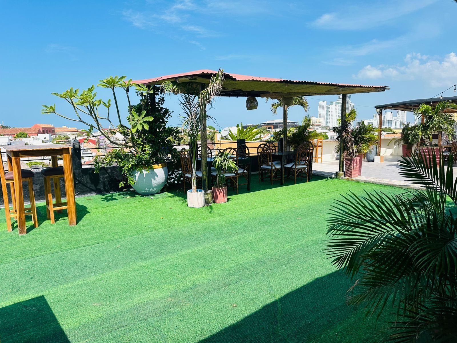 Une terrasse sur le toit, dotée d’un revêtement en gazon synthétique, de meubles en bois et de plantes en pot.