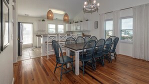 Une cuisine spacieuse avec des meubles blancs, une table à manger en bois et des chaises bleues.