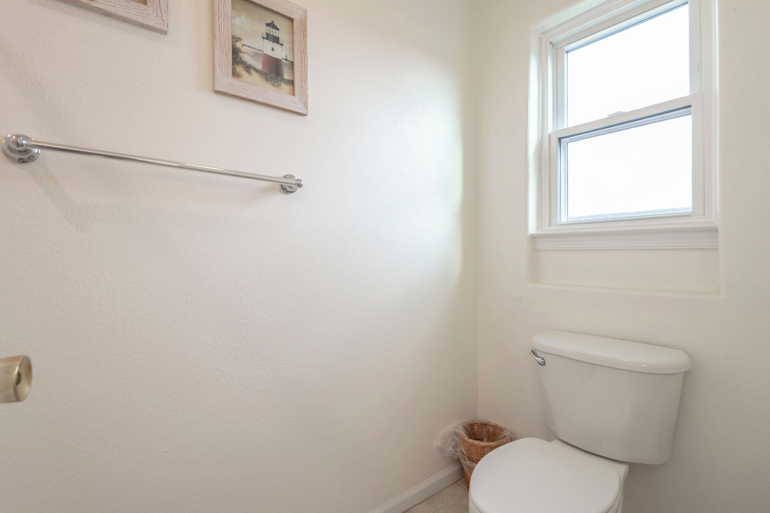 A bathroom with a white toilet, a window, and a towel rack.