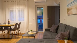 Un salon moderne avec un canapé gris, une table à manger avec des chaises et une petite table sur laquelle est posée une plante.