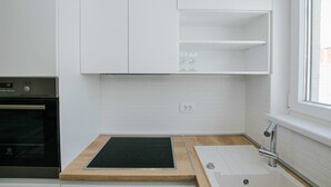 A kitchen with white cabinets, a built-in oven, a wooden countertop, and a window with a view. - Spacious Luxury Trogir Apartments - Classic Two Bedroom Apartment (Trogir)