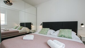 A hotel room with a large bed, two bedside tables, a mirror, and a window. - Spacious Luxury Trogir Apartments - Comfort Two Bedroom Apartment (Trogir)