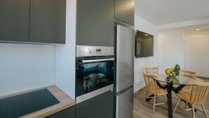 A modern kitchen with a built-in oven, a refrigerator, and a dining table with chairs. - Spacious Luxury Trogir Apartments - Superior Two Bedroom Apartment (Trogir)