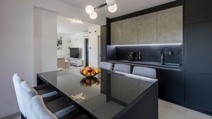 Una cocina moderna con una isla central, armarios negros y un frutero en la isla.