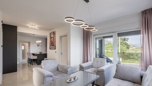 Una sala moderna con una mesa de centro de vidrio, dos sofás y un comedor al fondo.