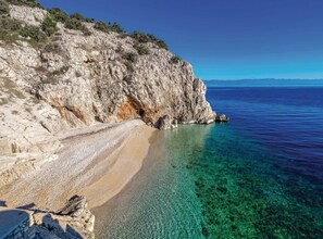 A coastal beach with clear turquoise water, a sandy shore, and rocky cliffs. - Cozy One Bedroom Apartment with Terrace (Brsec)