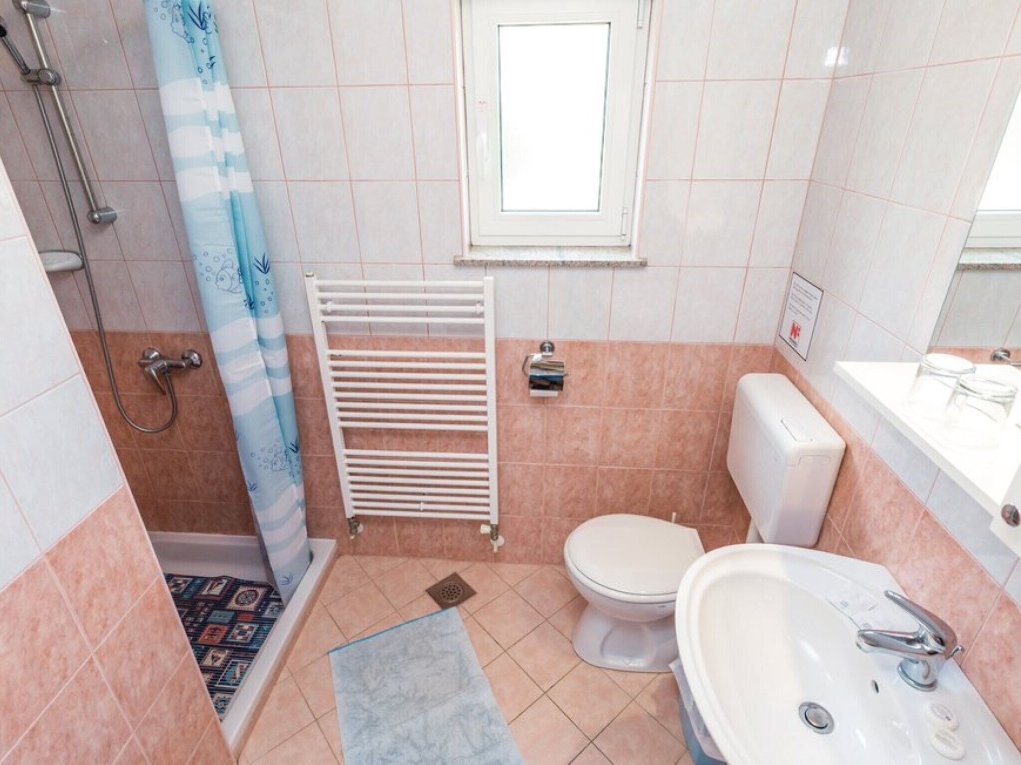 Ein Badezimmer mit Dusche, Toilette, Waschbecken und einem Handtuchhalter.