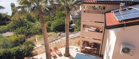 A hotel with a rooftop pool, solar panels, and a view of the sea.