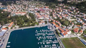 An aerial view of a coastal town with a marina filled with boats, surrounded by residential buildings and greenery. - Holiday Home Boni - Holiday Home (Rab)