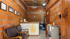 Un'area reception di un hotel con parete in mattoni, scrivania in legno e zona salotto.