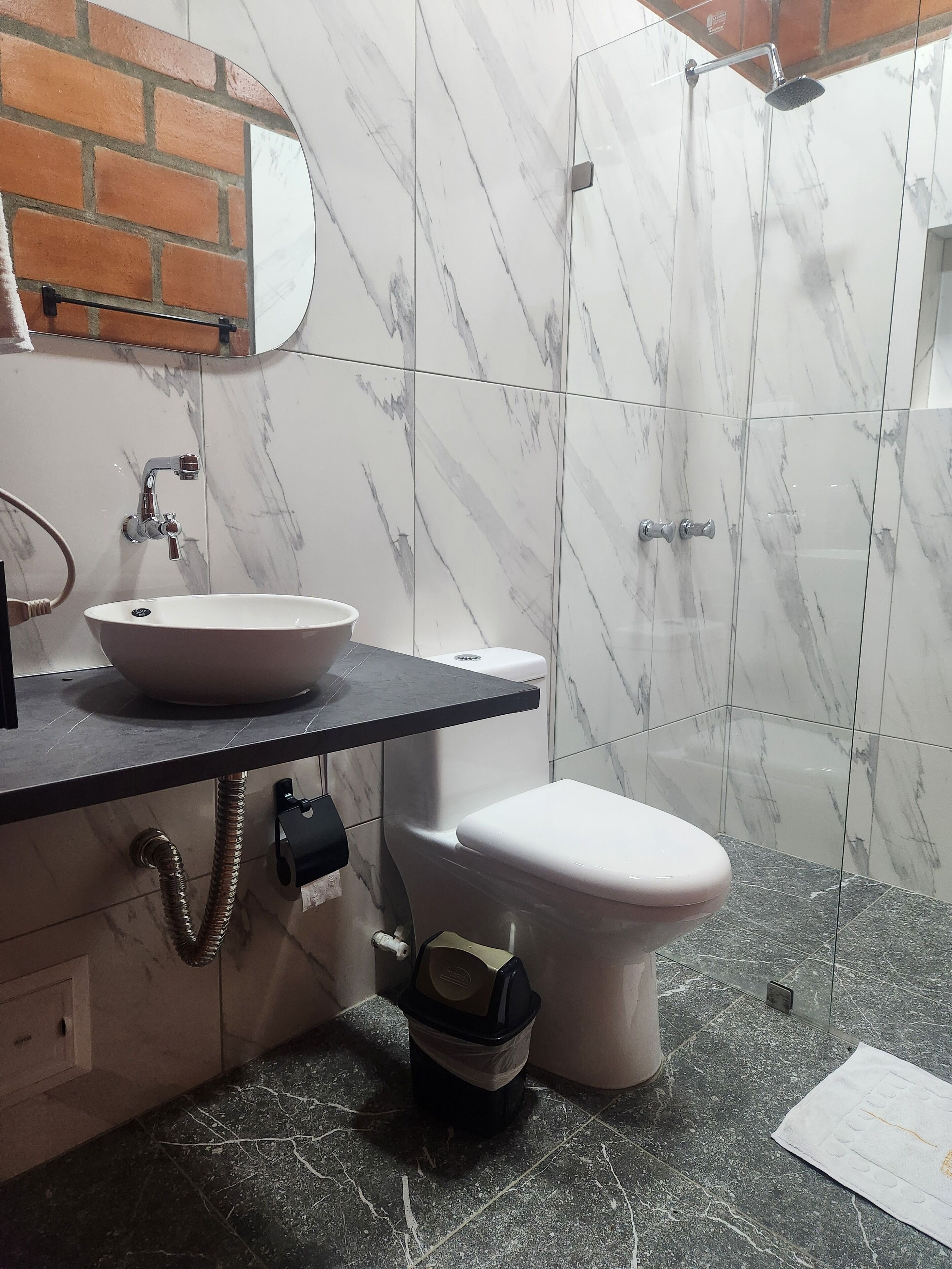 Et badeværelse med en hvid vask, toilet og brusebad.