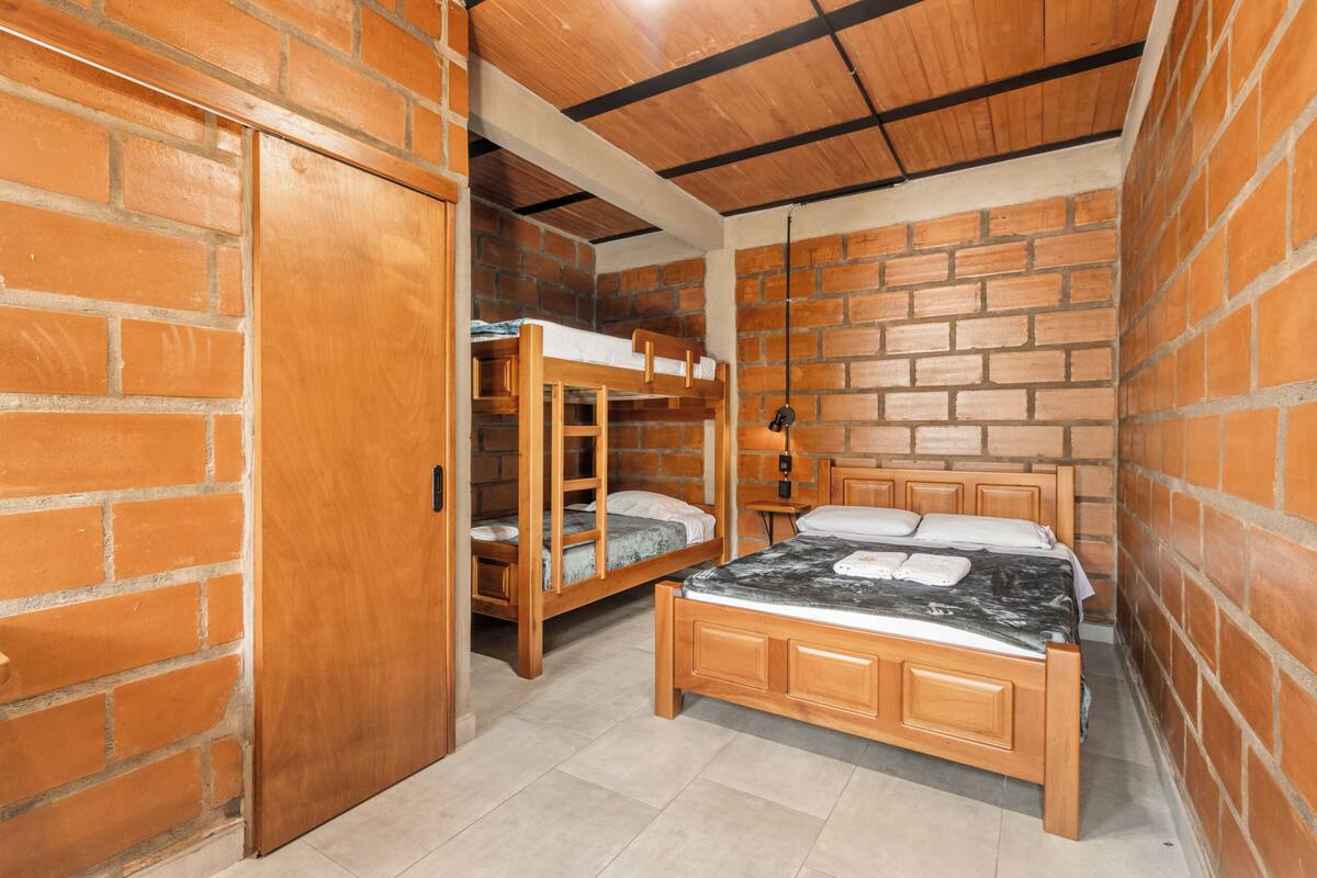 A room with a wooden bunk bed, a single bed, and a wardrobe.