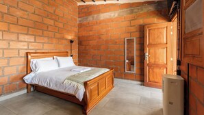 Camera da letto con parete in mattoni, letto di legno e un ampio guardaroba.
