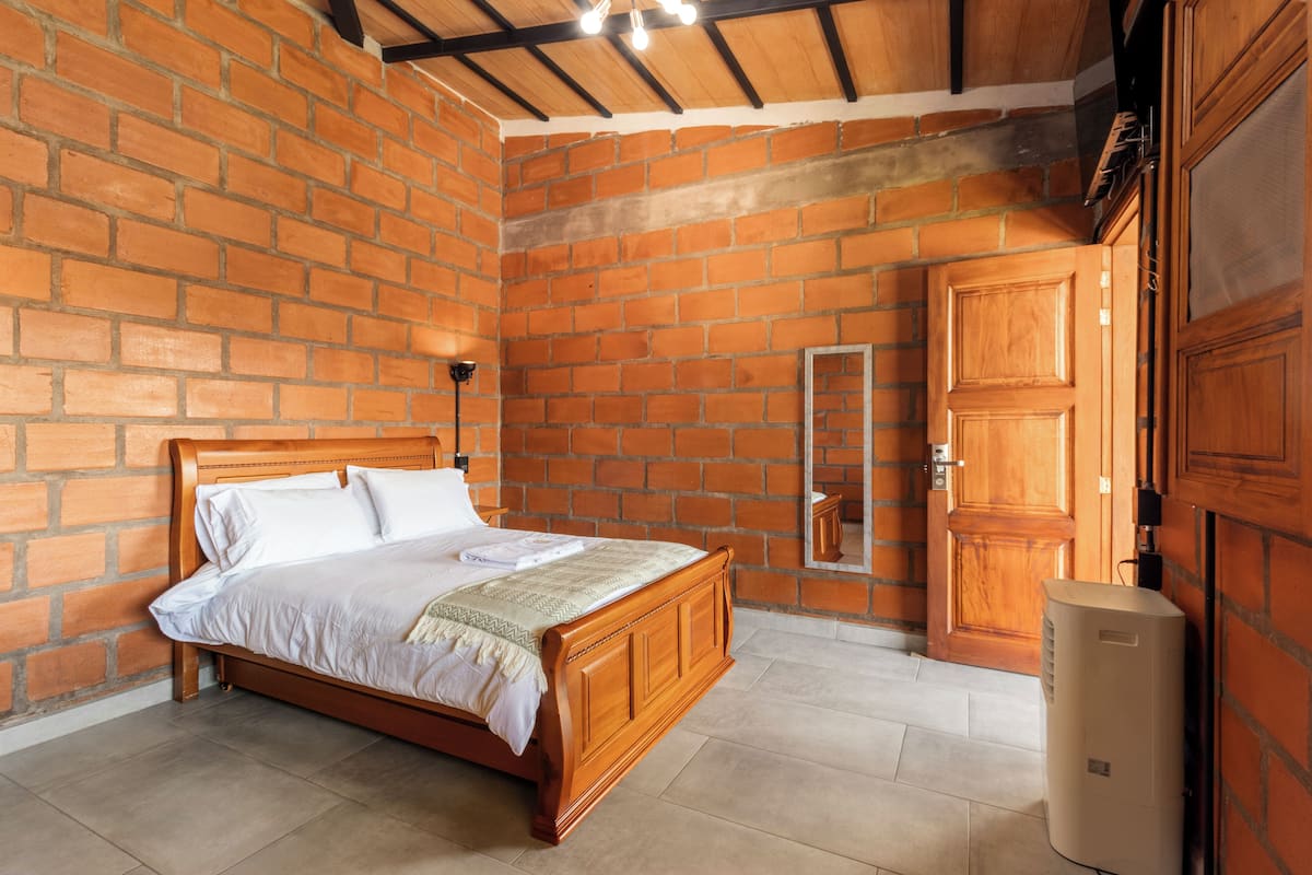 A bedroom with a brick wall, wooden bed, and a large wardrobe.