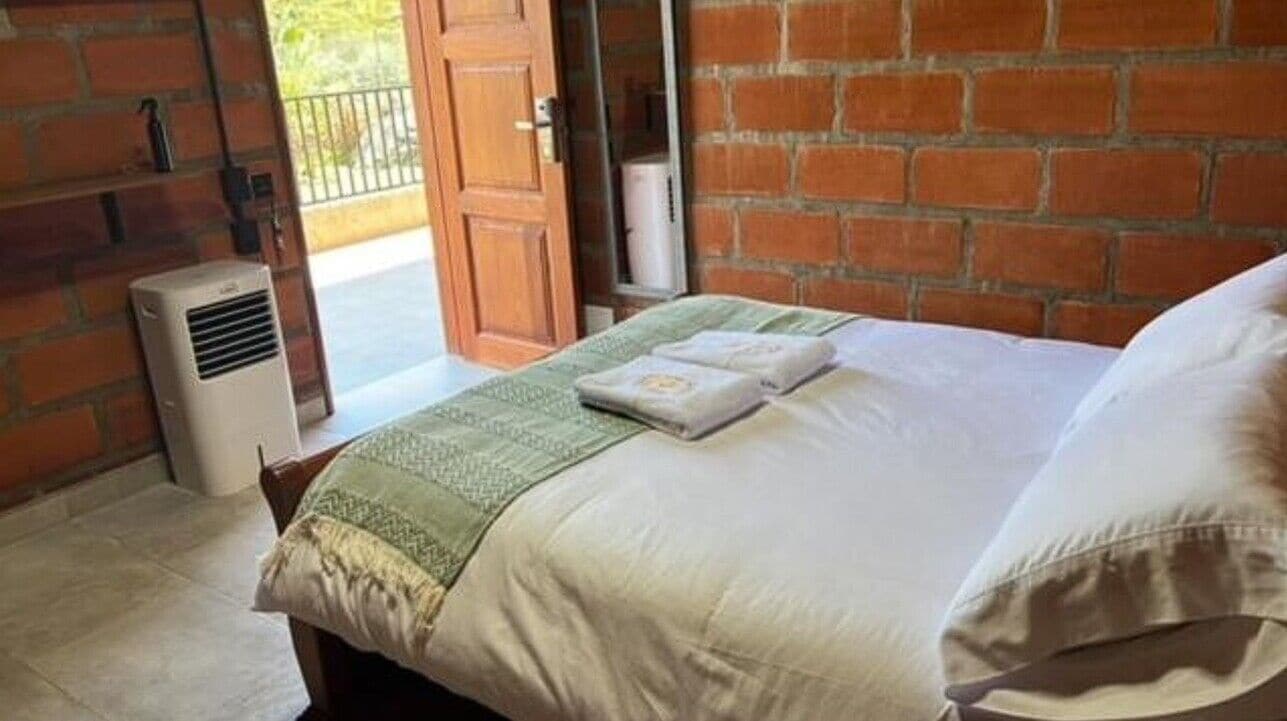 Une pièce avec un lit, un radiateur et un mur en briques.