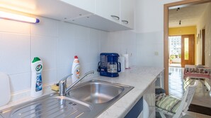 Una cocina moderna con un lavamanos doble, armarios blancos y una cafetera.
