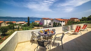 A terrace with a table set for breakfast, outdoor seating, and a view of the sea and hills. - Cozy Beachfront Holiday Home Slatine - Five Bedroom Holiday Home (Slatine)
