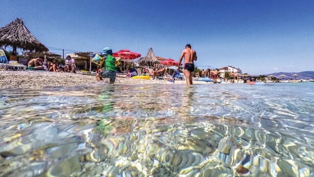 A beach scene with clear shallow water, umbrellas, and people. - Cozy Beachfront Holiday Home Slatine - Five Bedroom Holiday Home (Slatine)