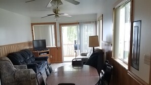 Ein Essbereich mit rundem Tisch und Stühlen, einer Couch, einem Fernseher und einem Deckenventilator.