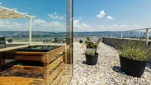 Une terrasse sur le toit, avec une table en bois, des plantes en pot et une vue sur le paysage urbain.