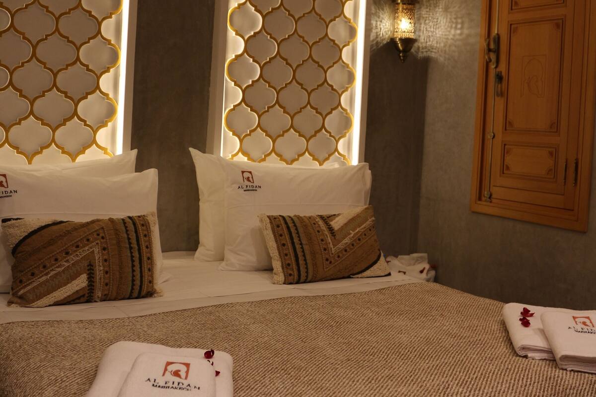 A hotel room with a patterned wall, a wooden door, and neatly folded towels on the bed.
