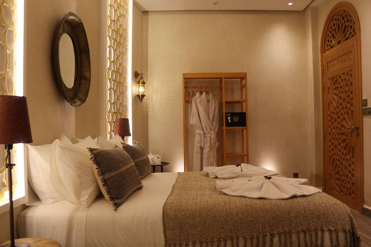 A hotel room with a bed, a wardrobe, and a mirror.