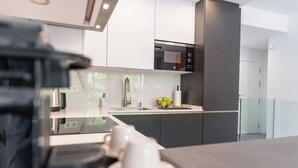 A modern kitchen with a sleek design, featuring a stainless steel sink, a microwave, and a bowl of fruit on the counter. - Modern 2-bedroom duplex apartment near Historical center (Málaga)