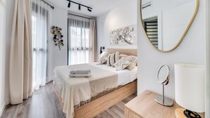 A modern bedroom with a bed, bedside table, lamp, and a mirror. - Modern 2-bedroom duplex apartment near Historical center (Málaga)