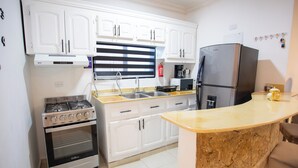 A kitchen with white cabinets, a stove, oven, sink, and a refrigerator.