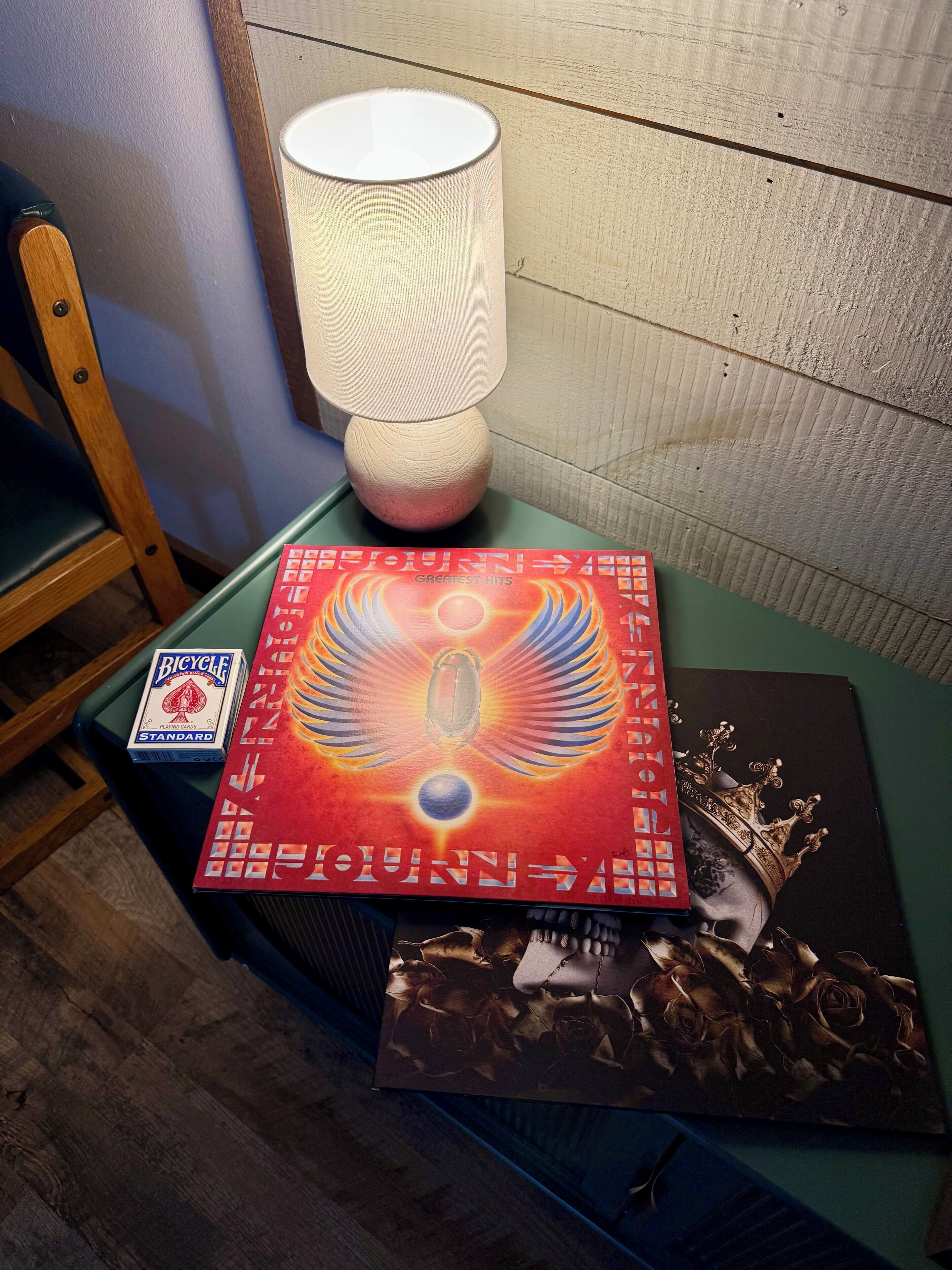 A table with a lamp, a deck of playing cards, and a CD case.